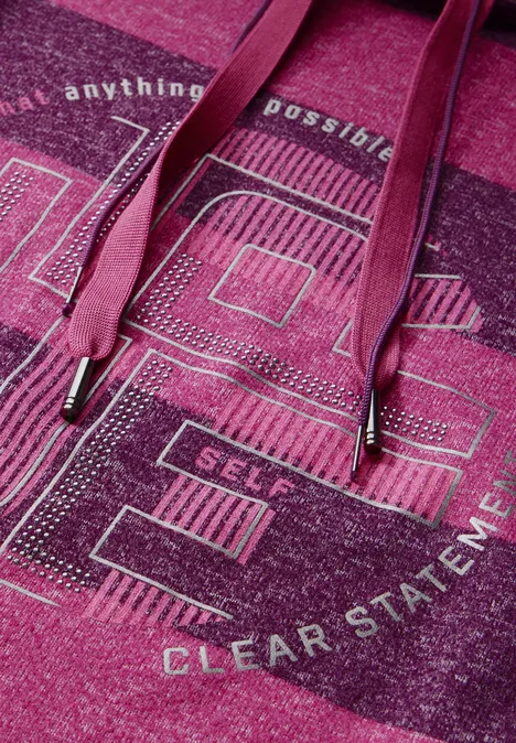 Nahaufnahme eines pinken Hoodies mit Glitzerprint und Schriftzug.